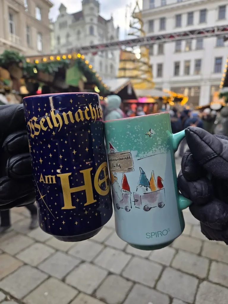 Two Vienna Christmas market mugs held in gloved hands