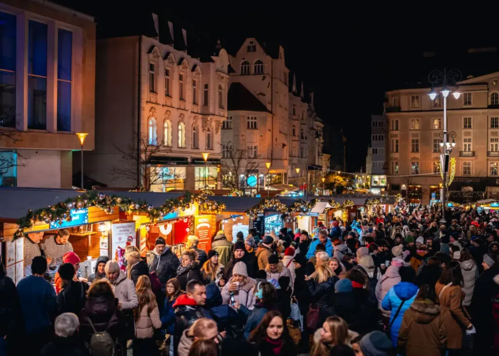 An evening crowd in coats and hats at the Zelný trh Christmas market in Brno